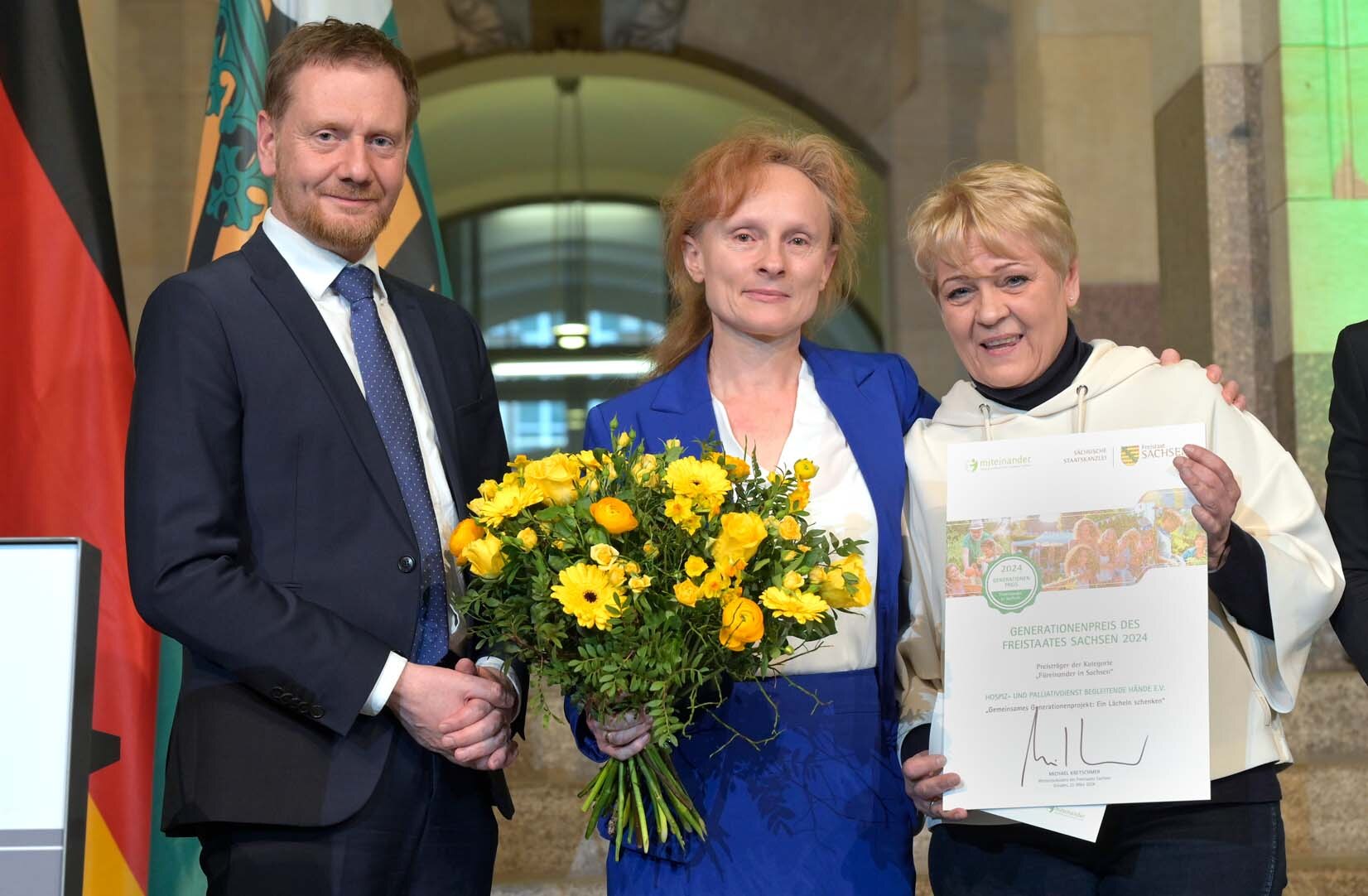 Zwei Frauen und ein Mann posieren für ein Foto.