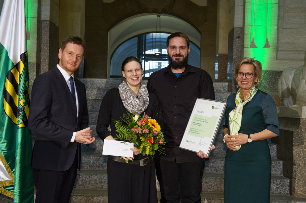 Zwei Männer und zwei Frauen stehen auf einer Bühne.