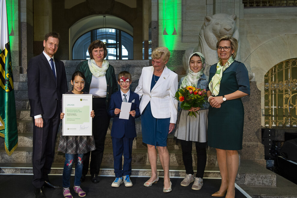 Ein Mann, zwei Frauen und drei Kinder stehen auf einer Bühne.