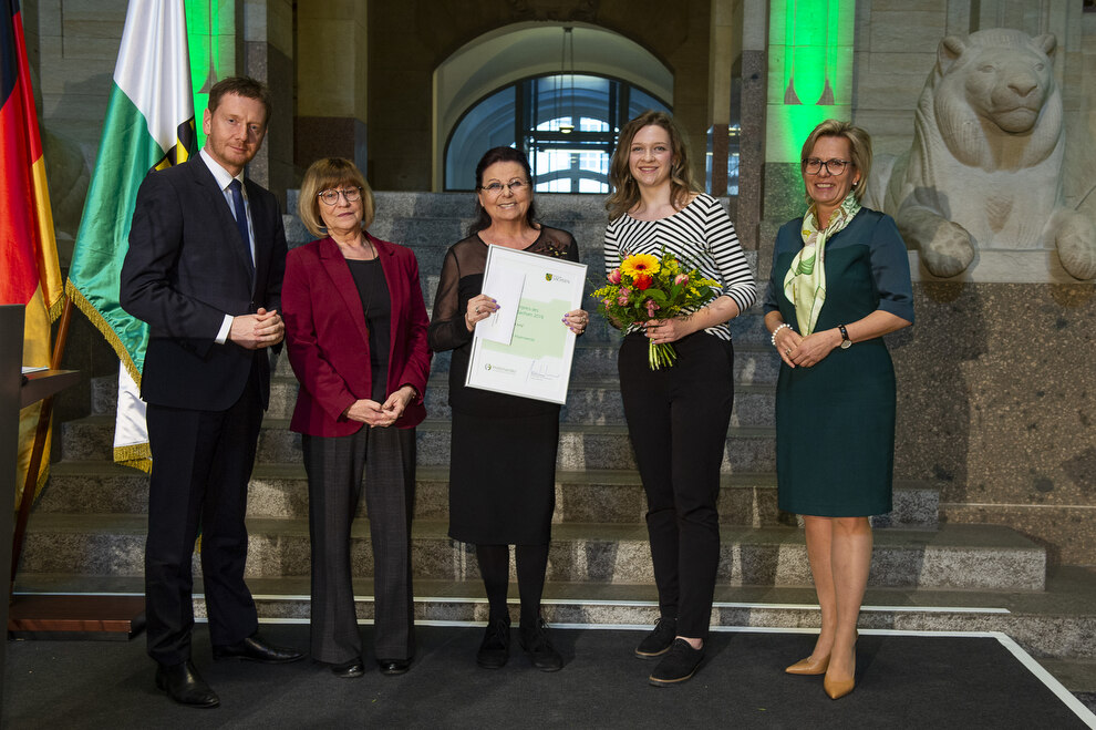 Männer und Frauen stehen auf einem Podium.